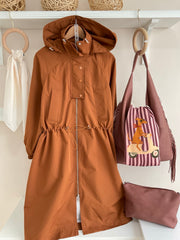 Gabardina Stocolm terracota presentada con bolso y accesorios