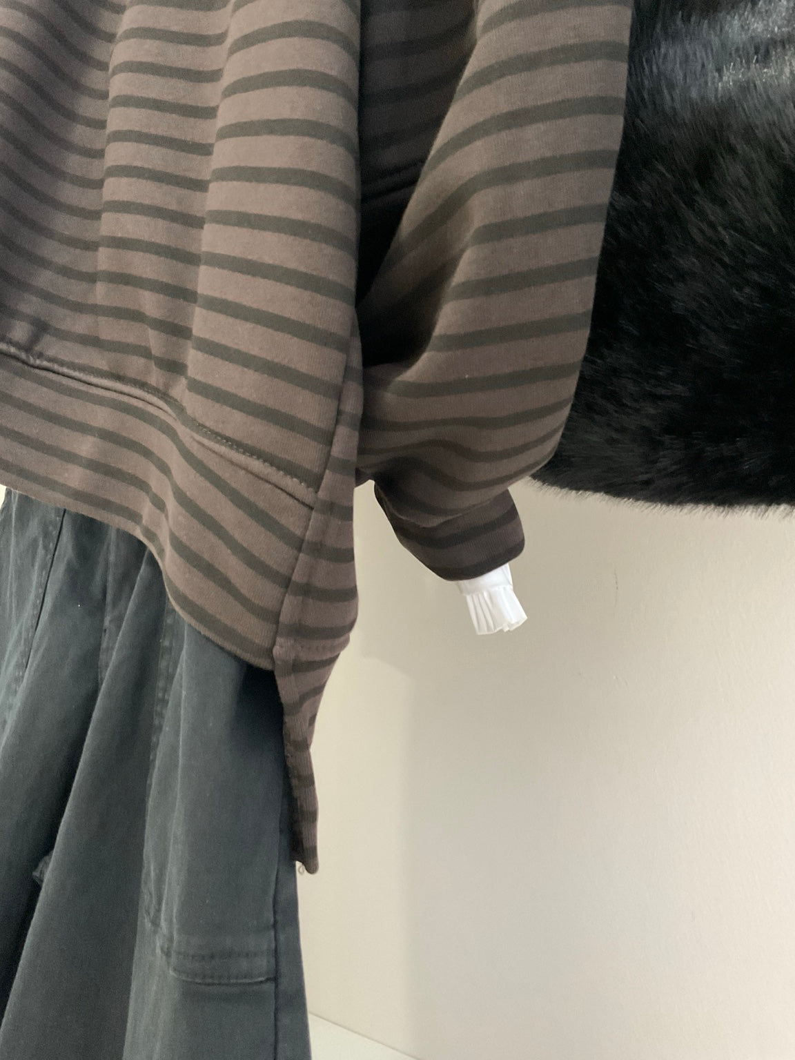 Detalle del bajo asimétrico de la sudadera de rayas chocolate y negro