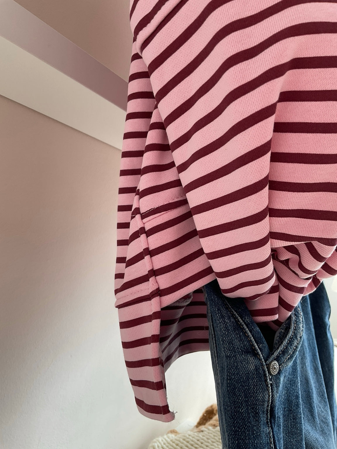 Detalle del bajo asimétrico de la sudadera de rayas rosa y burdeos