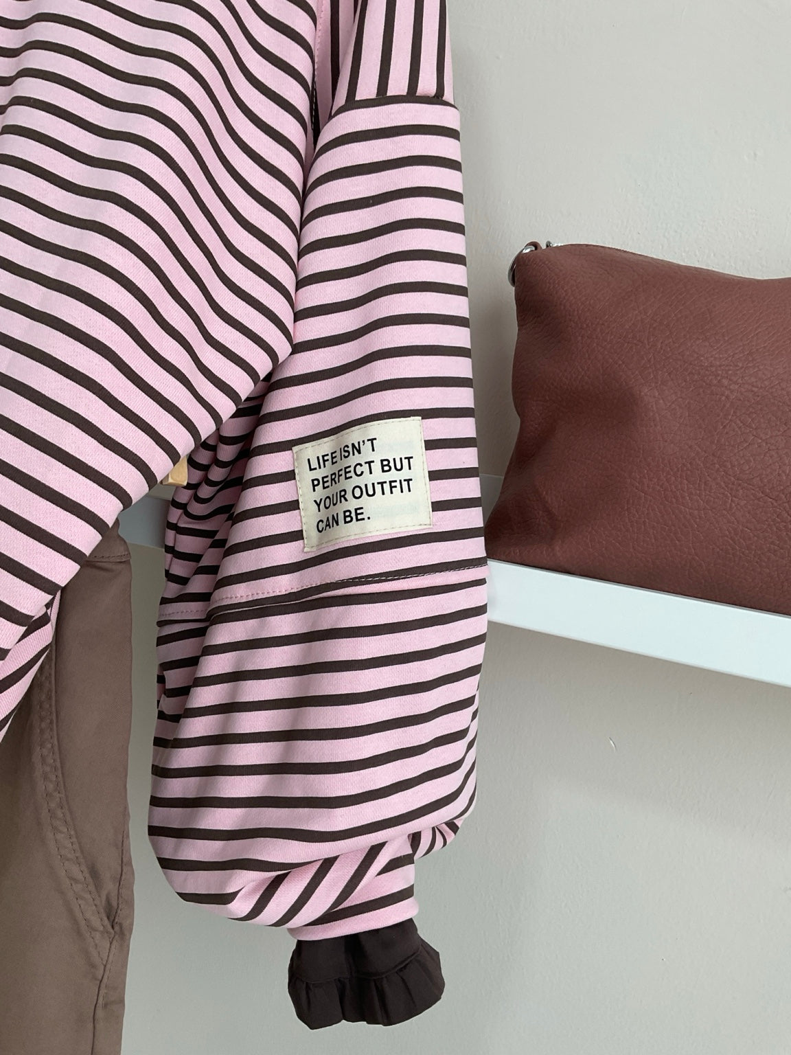 Detalle de manga y etiqueta decorativa de la sudadera rosa y chocolate